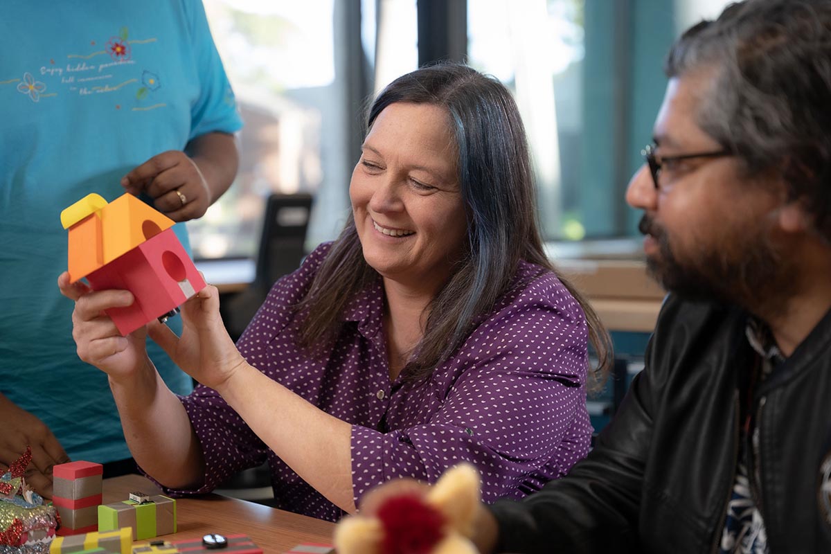 Load video: Introducing TapeBlock video: Image of a woman with dark hair holding a colourful foam block house.