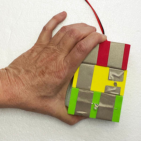 A hand holding red, yellow light sensor and green light TapeBlocks with a cable coming off the top.