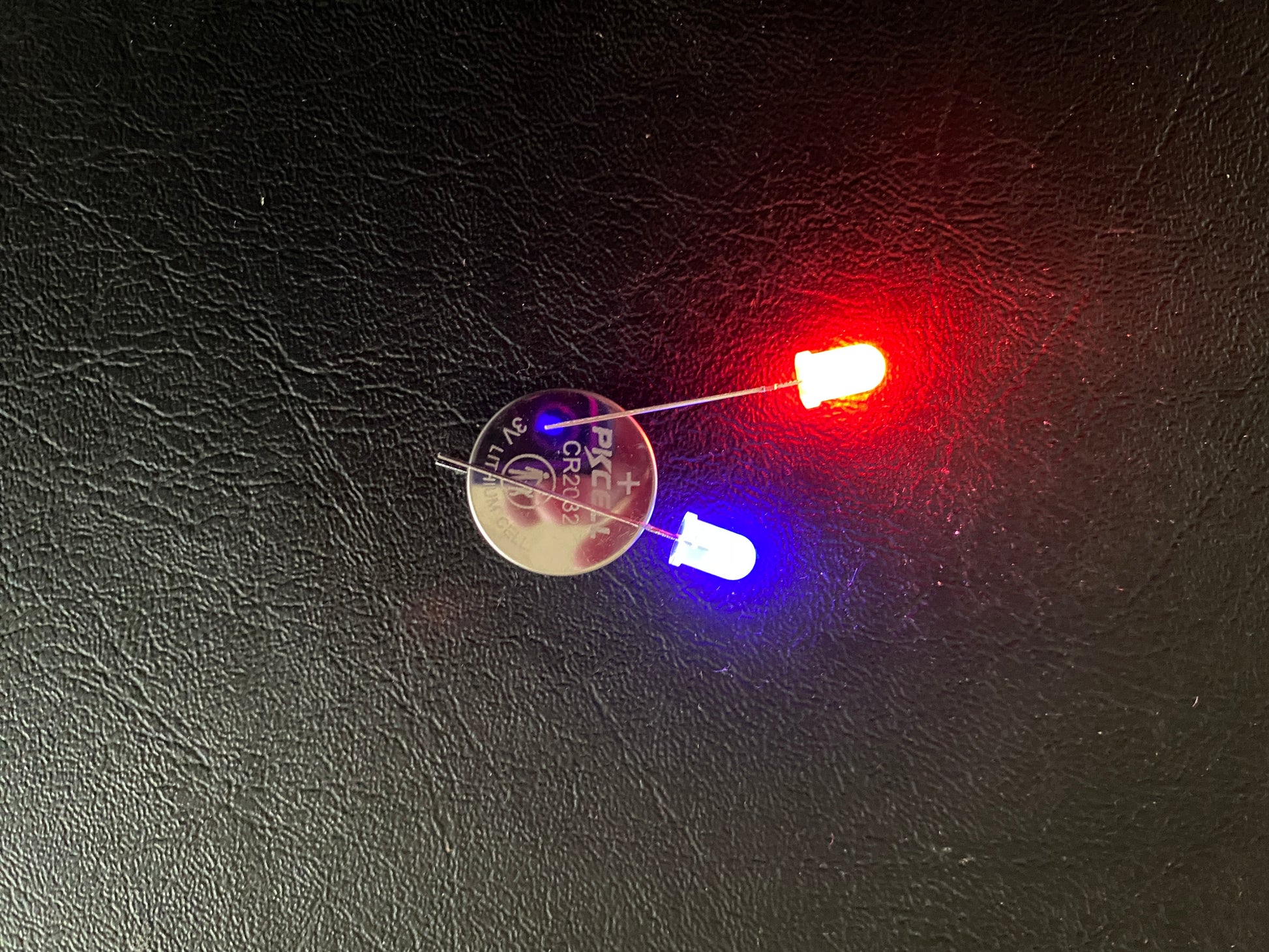 Red and Blue LEDs with legs of different lengths around a 3v Battery