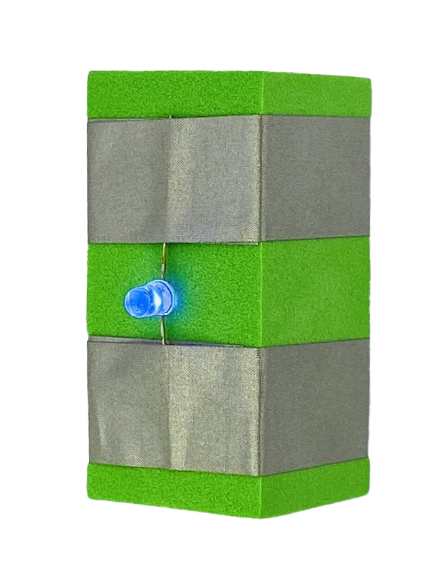 A green foam block with two parallel rows of conductive tape wrapped around it. There is a blue Light emitting diode (LED) that is connected between the two pieces of tape.  