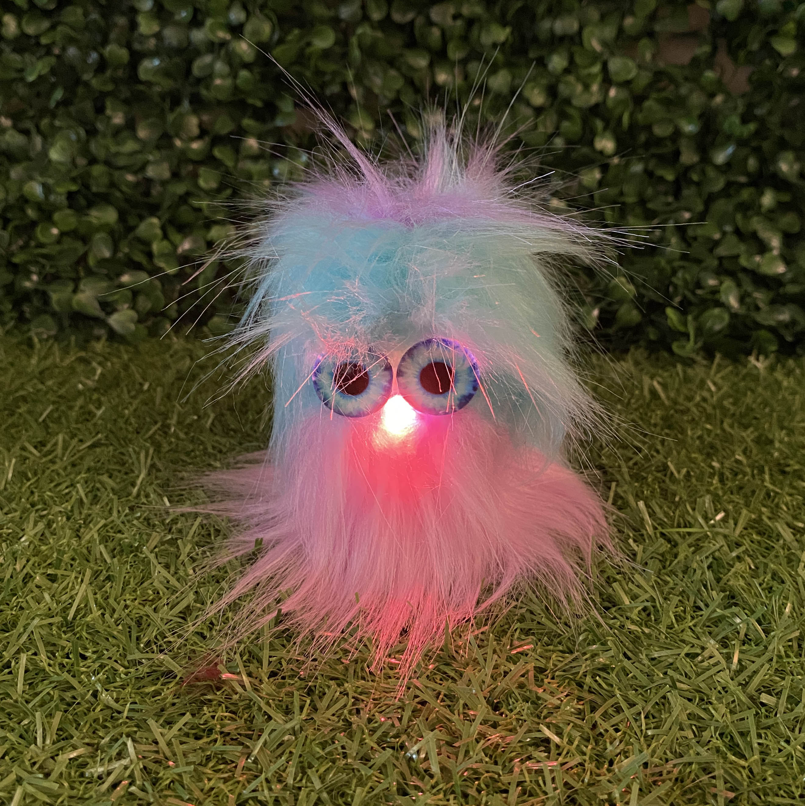 Pink and Blue Fur TapeBlock with blue eyes and red light up nose. closeup of it sitting in the garden