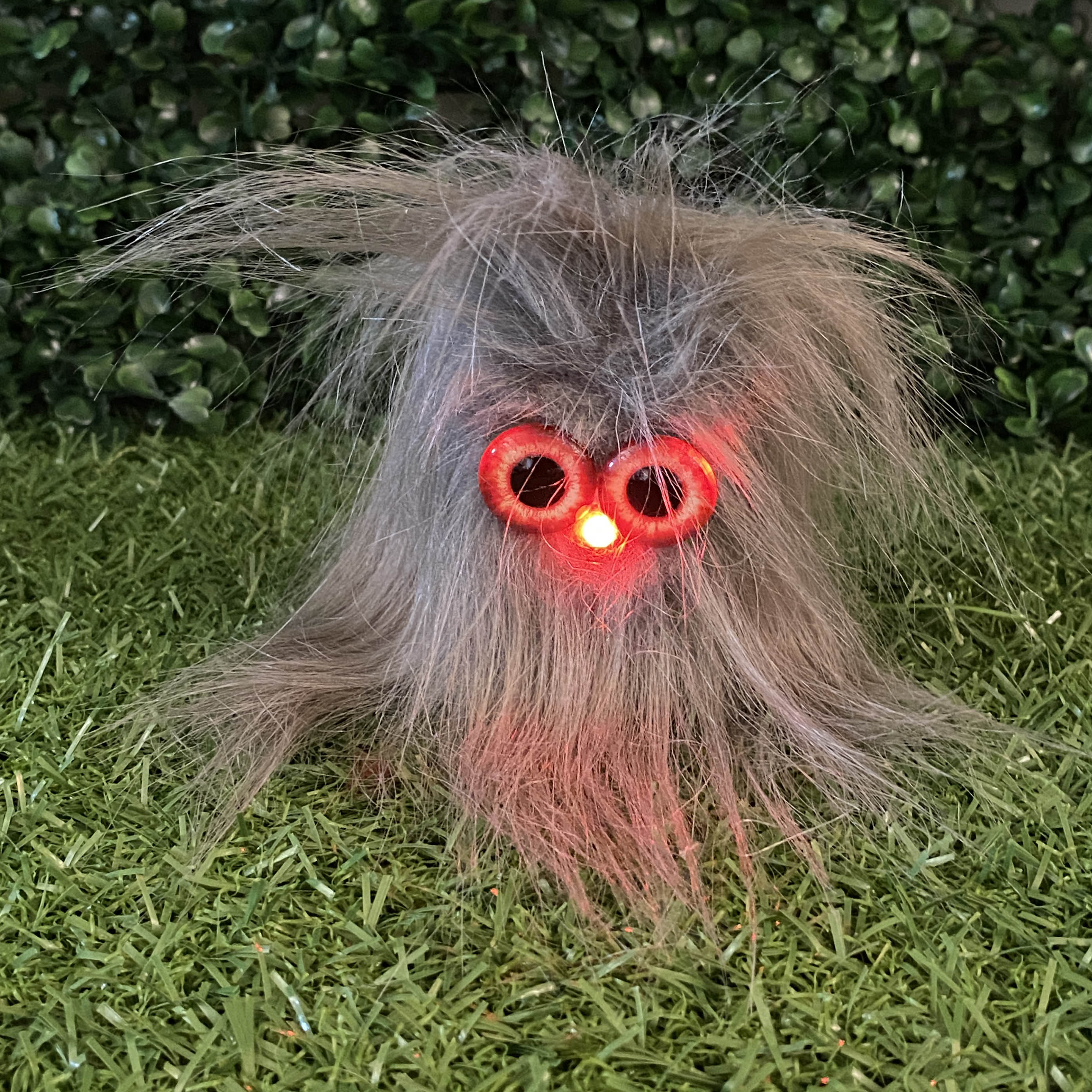 Grey fur TapeBlock with red eyes and red light up nose, sitting on the grass