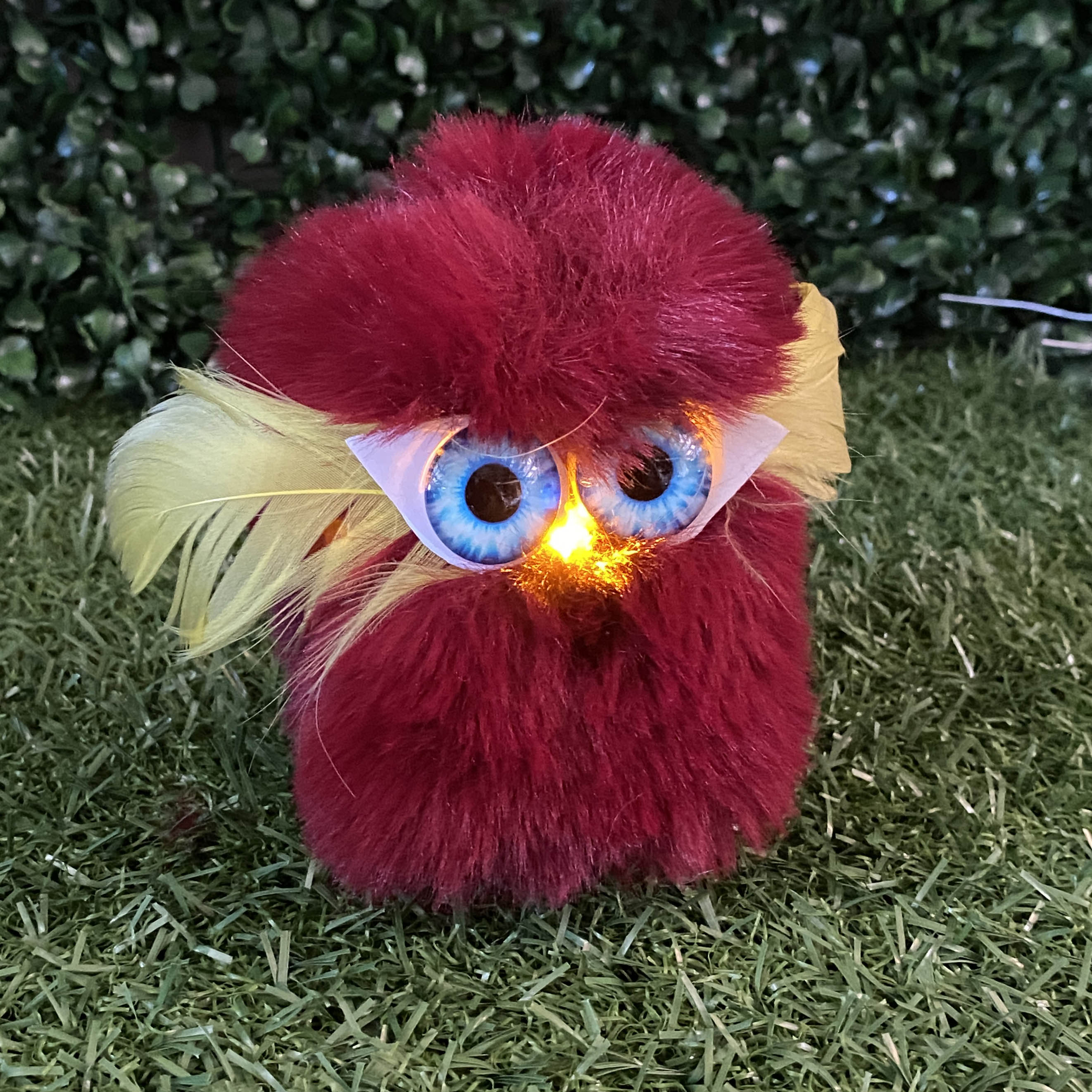 Red Fur TapeBlock with blue eyes and yellow light up nose, It is sitting on the grass