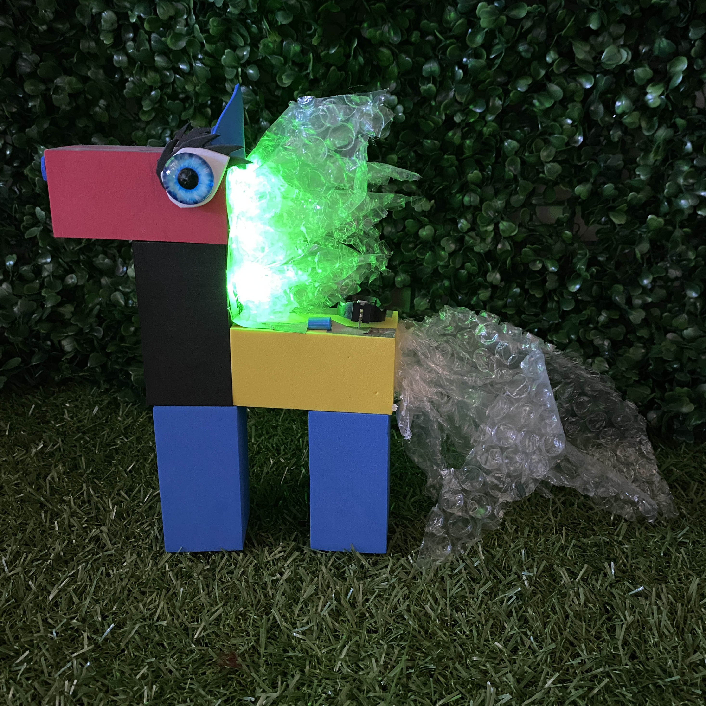 TapeBlock horse with blue glass eyes and green light up mane, It is sitting on the grass