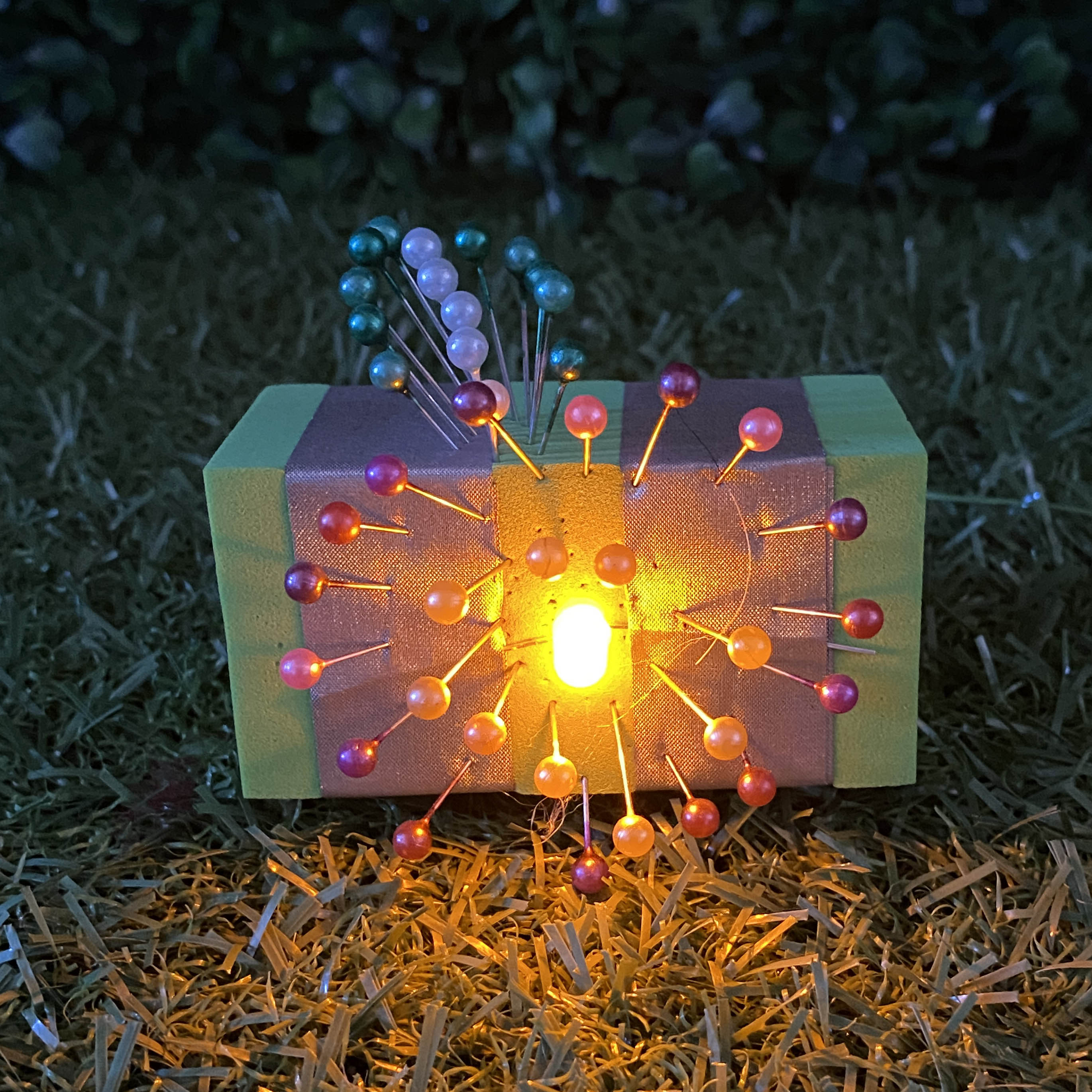 TapeBlock with pink pins and yellow light, It is sitting on the grass