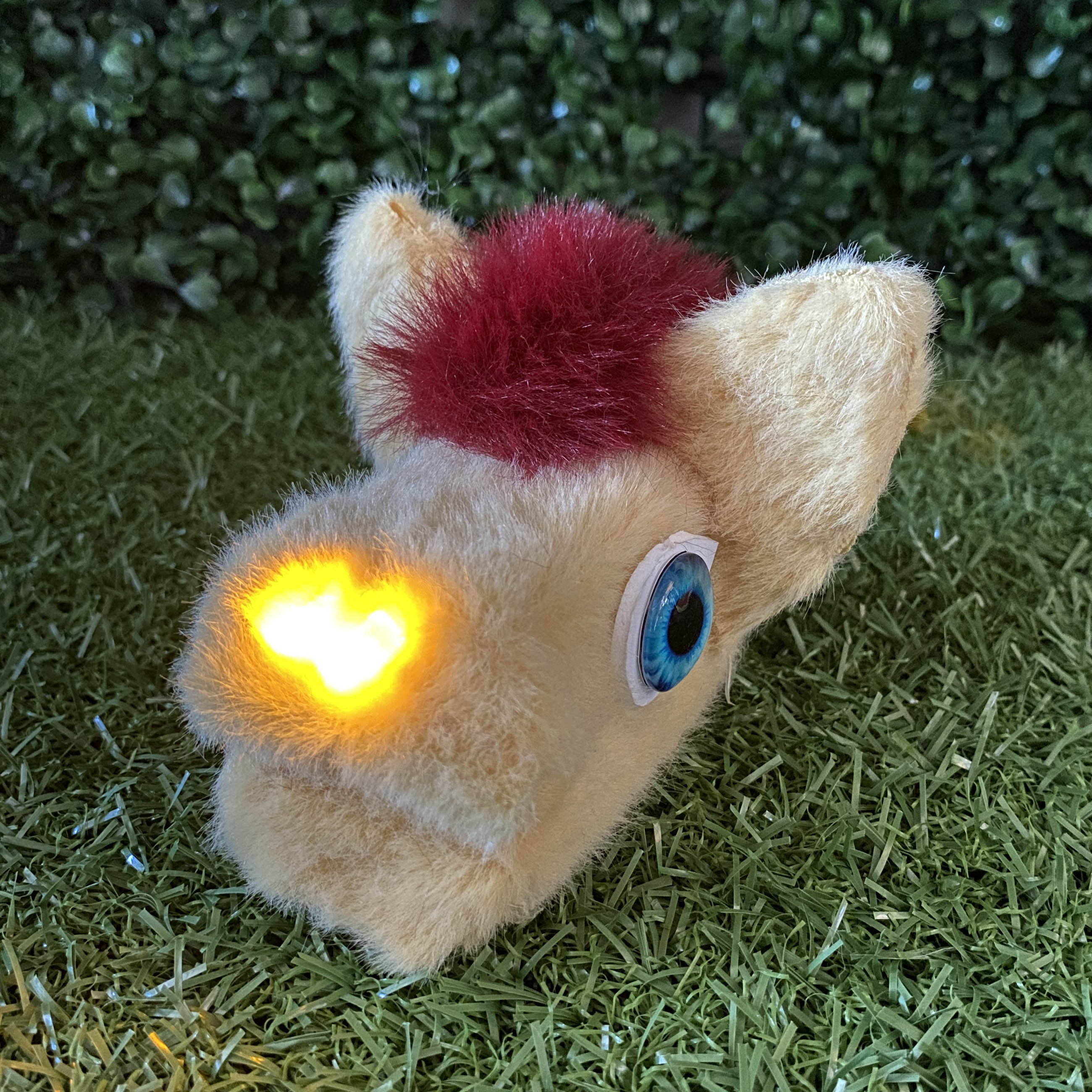 Tan fur horse head shaped TapeBlock with blue eyes and yellow light up nose, sitting on the grass