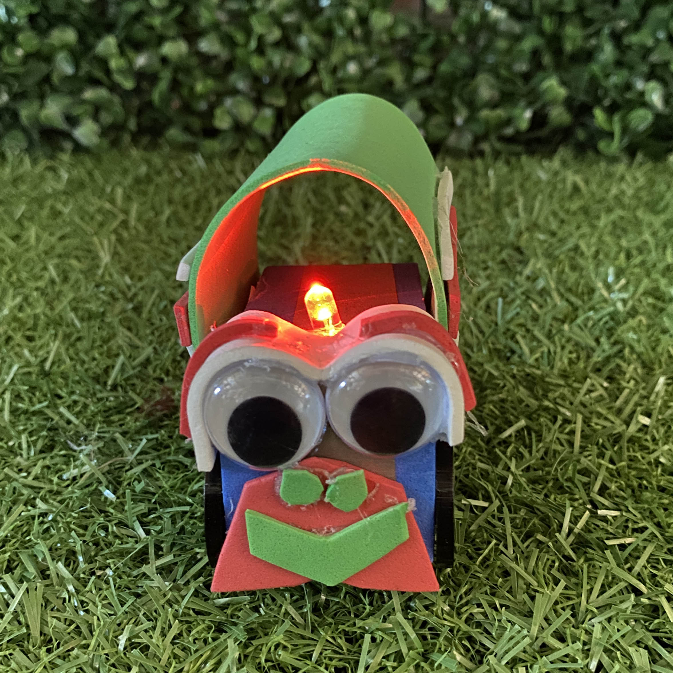 TapeBlock Train with black and white eyes and red light up funnel, It is sitting on the grass