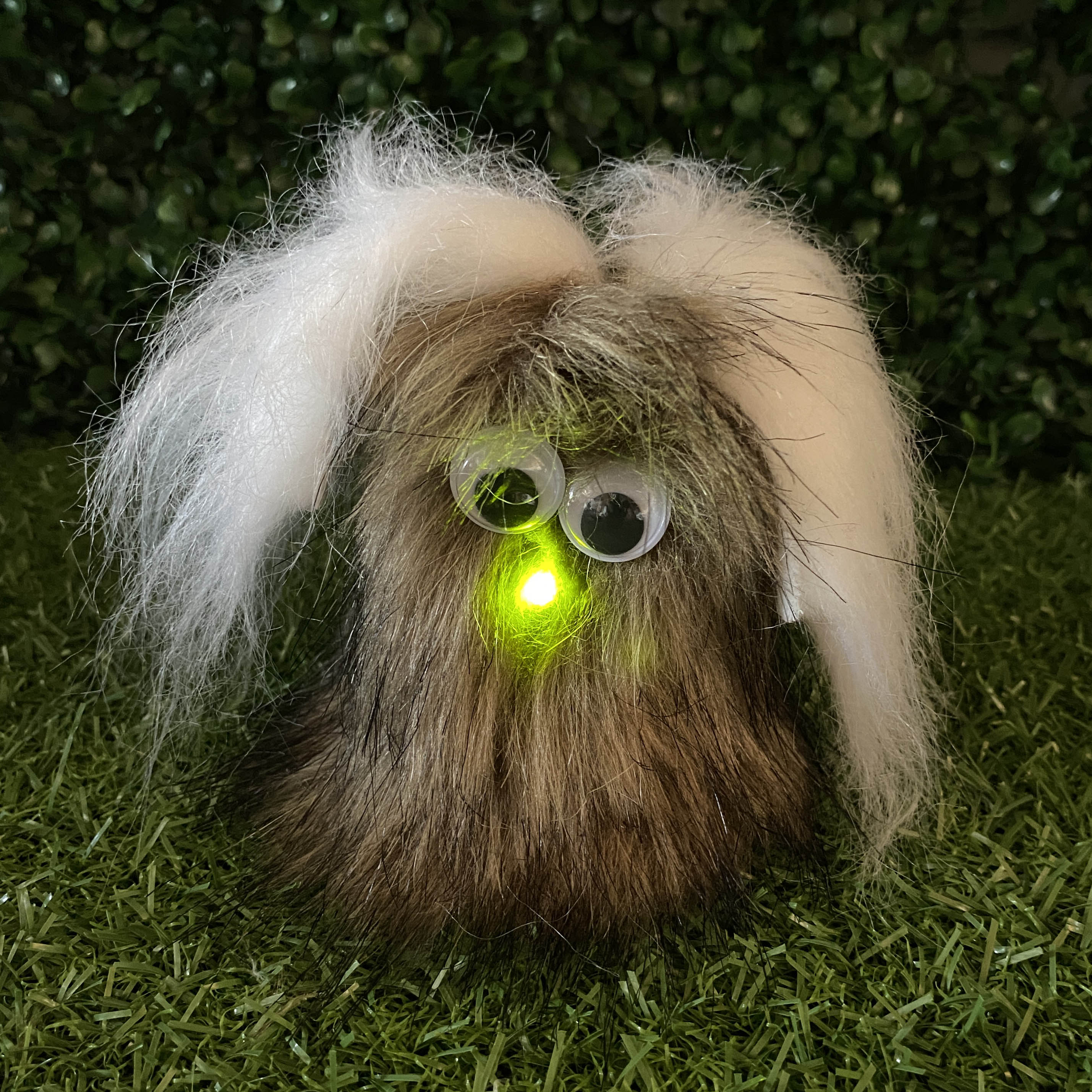 Brown fur TapeBlock with white ears, google eyes eyes and green light up nose, sitting on the grass