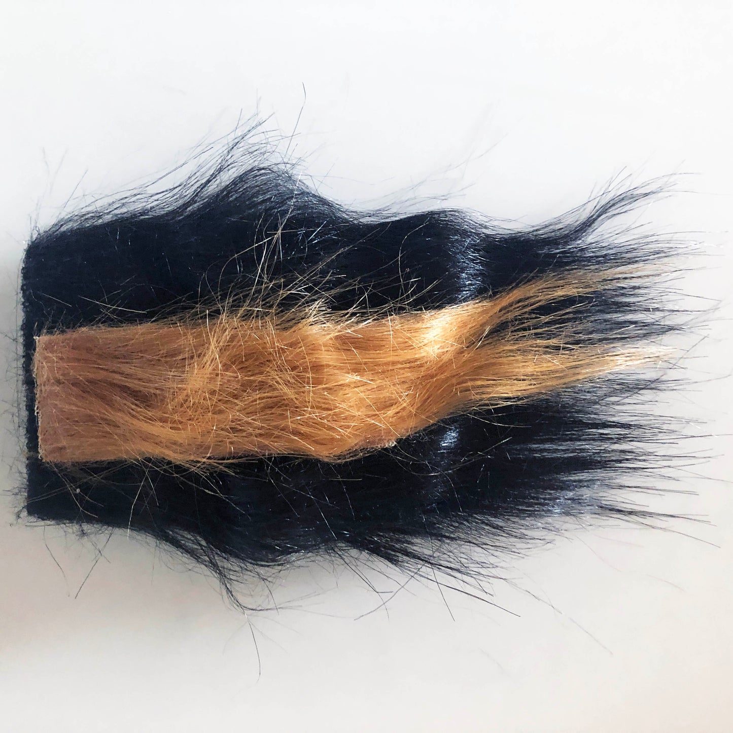 A small square of black fur with a separate piece of brown down the middle