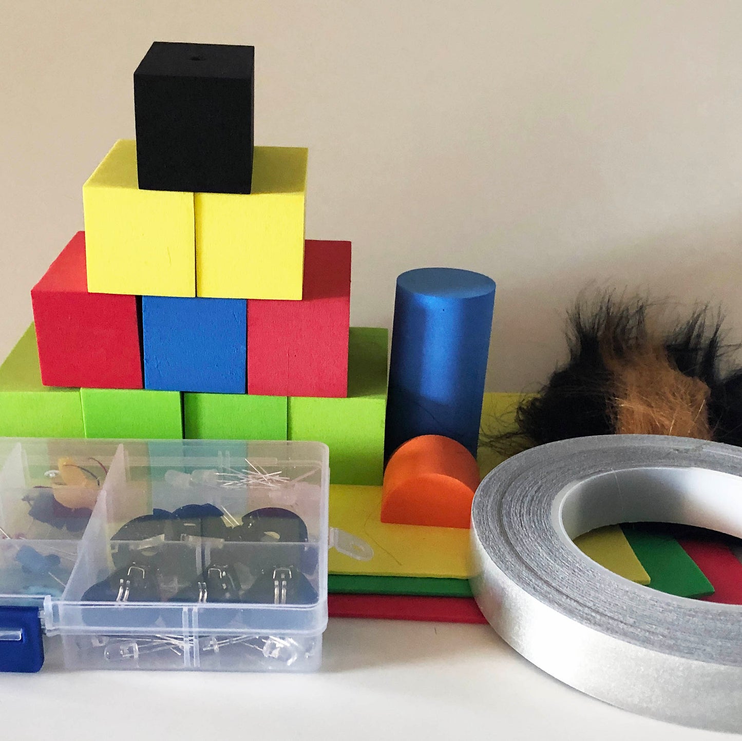 Contents of the TapeBlock making kit in a pile including Foam Blocks and sheet foam, LEDs, switches, motors and conductive tape, fur and eyes are included. You can see more of the fur and tape in this photo and the small components are in the plastic box
